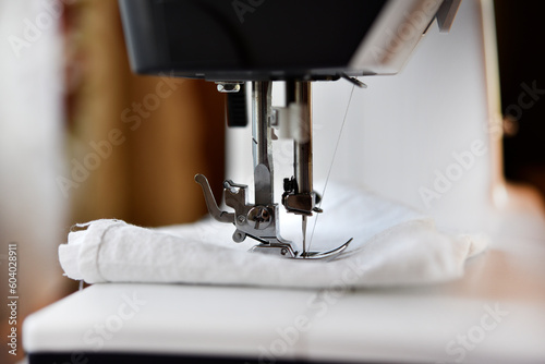 A white sewing machine in the room. Processing of clothes with a sewing machine.