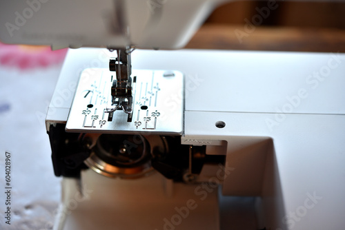 A white sewing machine in the room. Processing of clothes with a sewing machine.