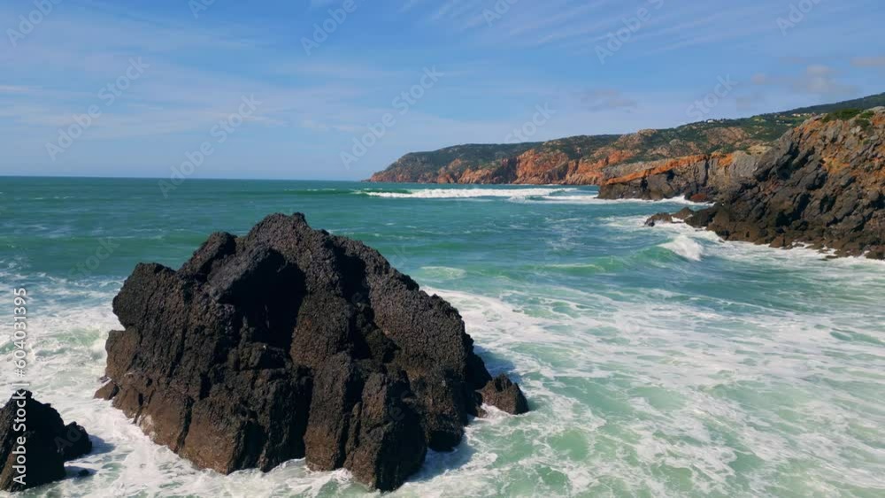 Sunny rocky coastal landscape with blue sea splashing on rough cliffs aerial. Sunny rocky coastal landscape with blue sea splashing on rough cliffs aerial.