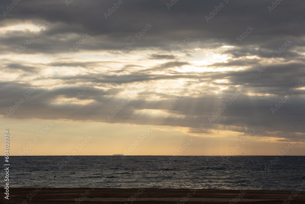 landscape of sunrise or sunset on the beach, the sun's rays breaking through the clouds