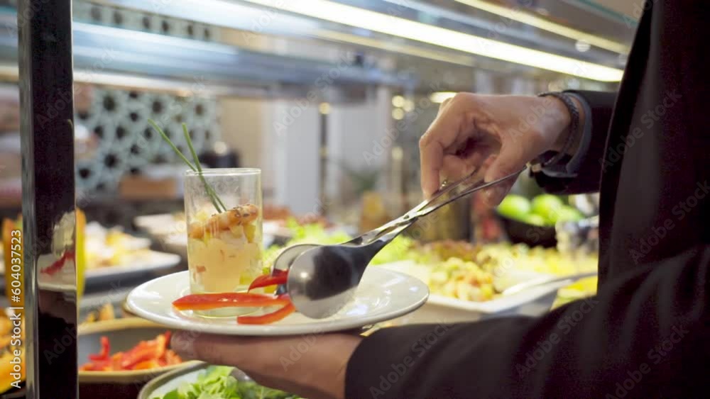 Man picks up a plate of food from a buffet in a luxury restaurant with colorful fruits and vegetables. Slow motion close up Man picks up a plate of food from a buffet in a luxury restaurant with colorful fruits and vegetables. Slow motion close up