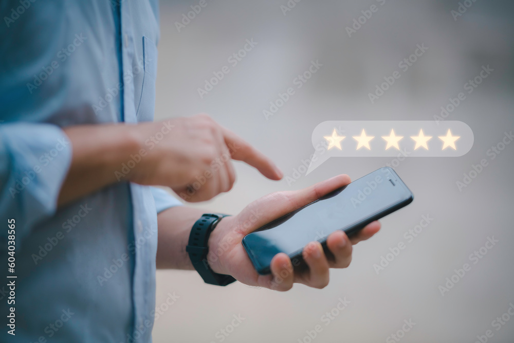 Customer service experience and business satisfaction survey.close up Man hand using smartphone with popup five star icon for feedback review satisfaction service.