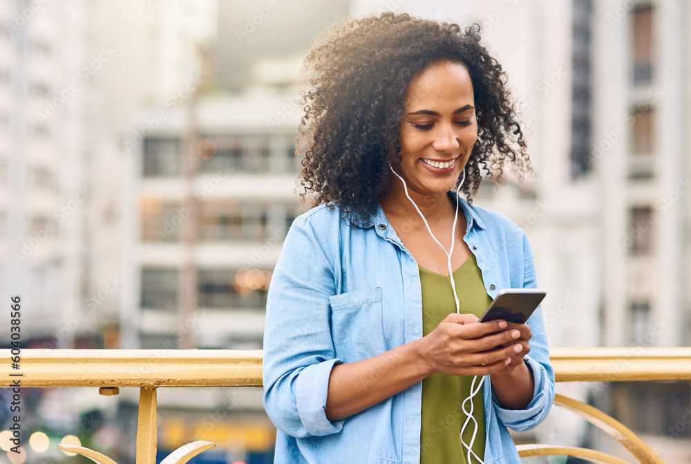 © Tamani Chithambo/peopleimages.com - Phone, music and woman in city with happiness listening to track, audio and song in urban town. Traveling, online and happy African female person streaming radio for relax, chill and peace on weekend