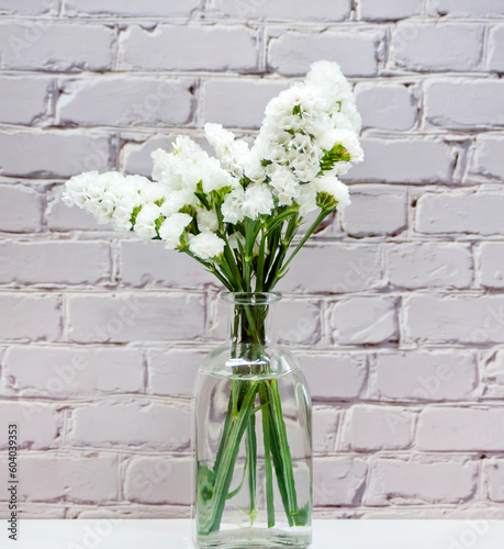 Jarrón de cristal con flores blancas de statice photo
