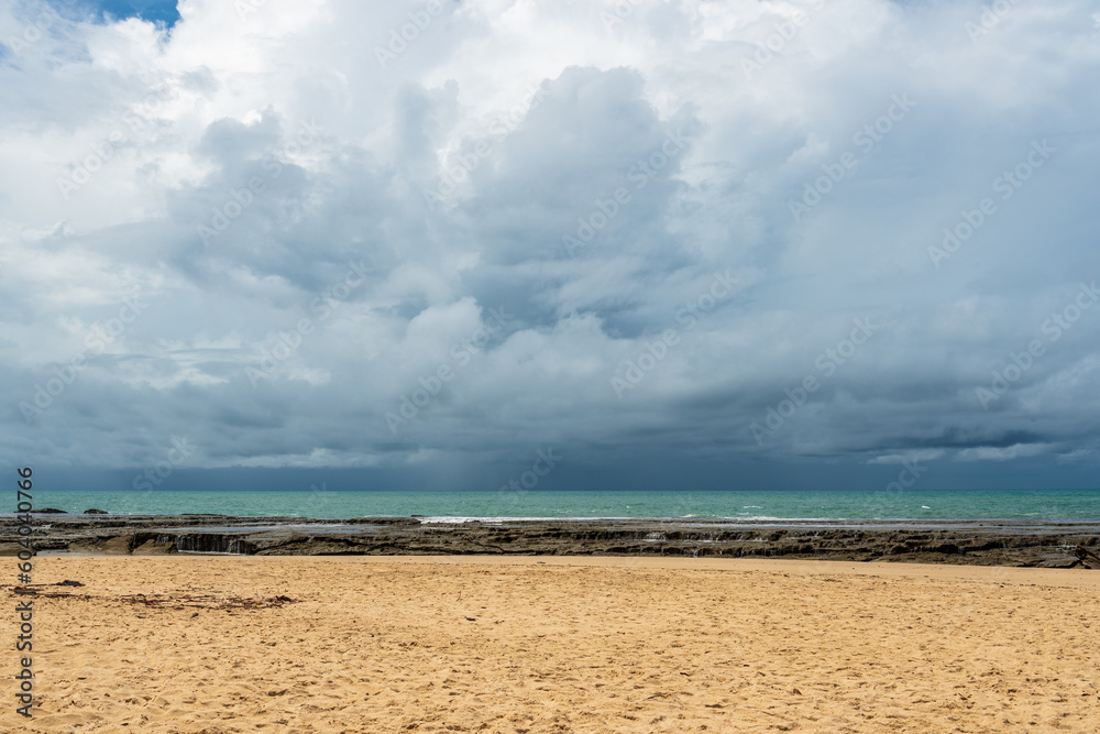 Rainy sky above brazilian beach surrounded by rocky barrier 