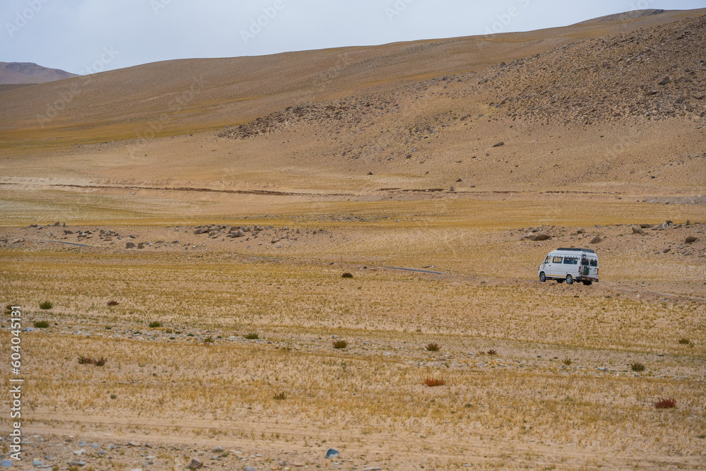 Obraz premium car driving through the desert. Landscape of Desert mountains against clouds sky at Ladakh, India