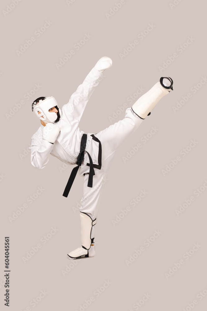 Vertical studio shot of young man wearing dobok and performing a kick. Vertical studio shot of young man wearing dobok and performing a kick.