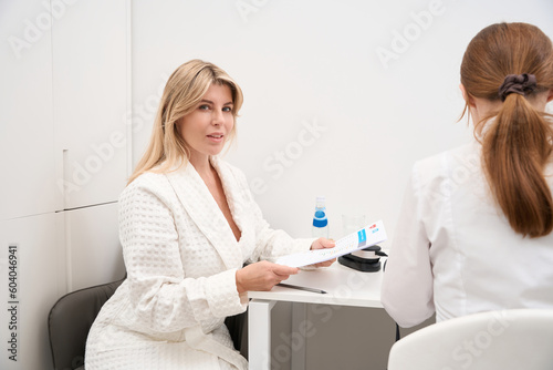 Two ladies are sitting at a desk in medical facility