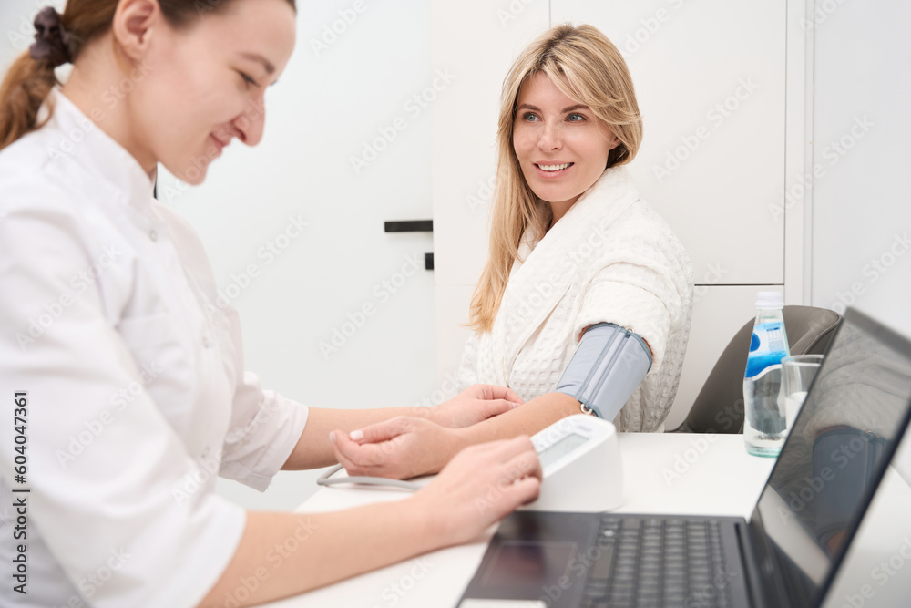 Young doctor measures blood pressure to female patient Young doctor measures blood pressure to female patient