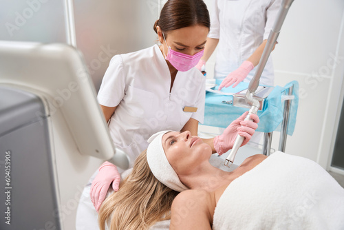 Female in a protective mask performs laser skin resurfacing procedure