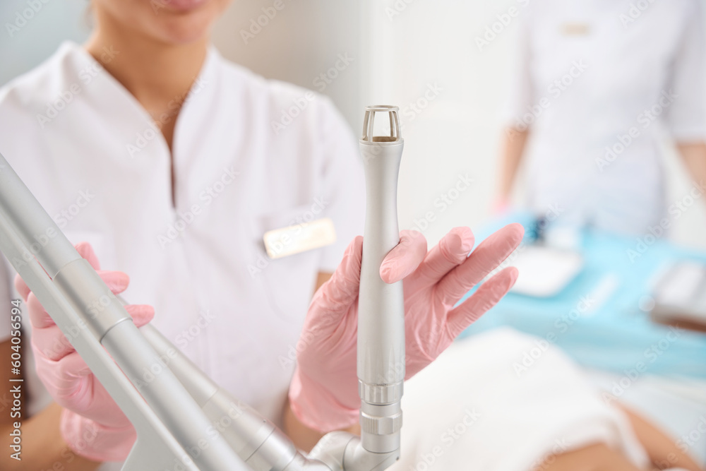 Employee aesthetic medicine clinic holds laser peeling tool in her hand Employee aesthetic medicine clinic holds laser peeling tool in her hand