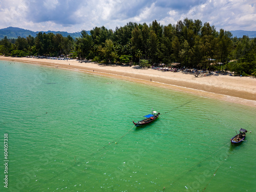 Fototapeta Naklejka Na Ścianę i Meble -  Colorful longtail boats in a shallow, tropical ocean next to palm trees and a sandy beach