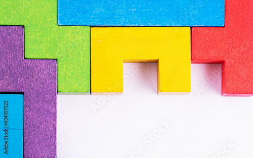 Different colorful shapes wooden blocks on white background, flat lay, copy space. Geometric shapes in different colors, top view.