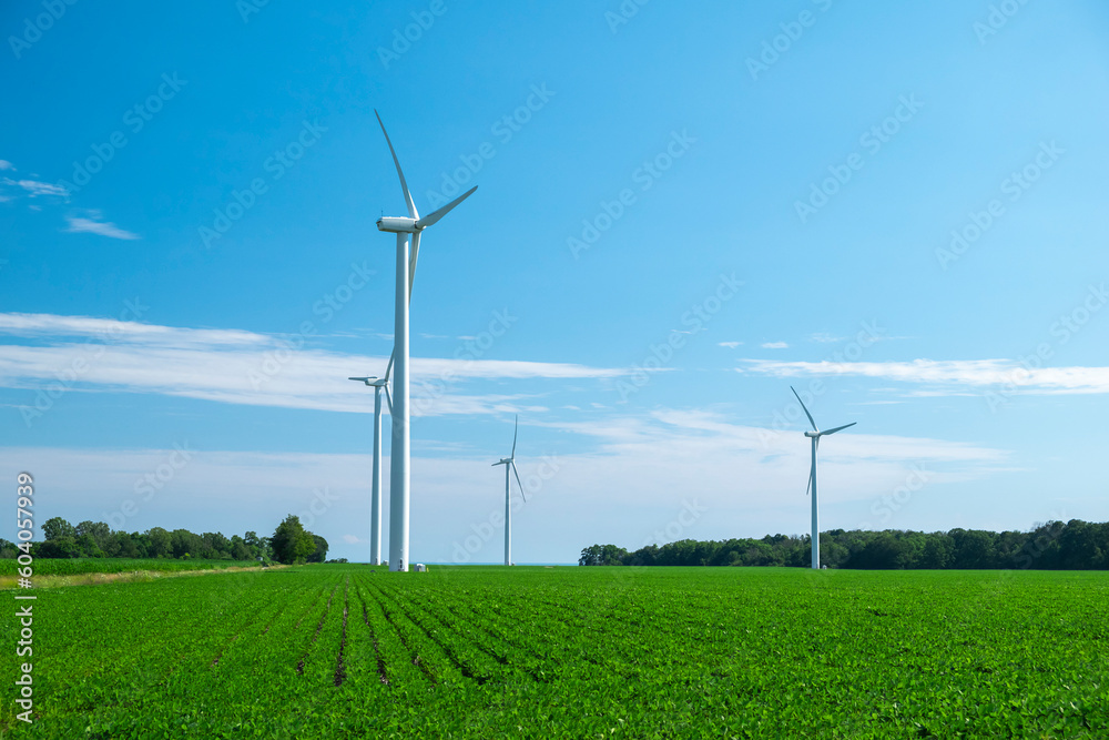 Close view of onshore horizontal axis wind turbine (windmill) in green field, deep blue sky, sunny day. Ontario Canada. Replenishable, green, renewable, alternative energy and natural sources concept. Close view of onshore horizontal axis wind turbine (windmill) in green field, deep blue sky, sunny day. Ontario Canada. Replenishable, green, renewable, alternative energy and natural sources concept.