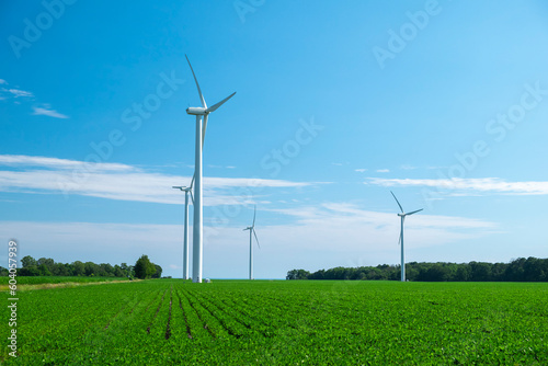 Close view of onshore horizontal axis wind turbine (windmill) in green field, deep blue sky, sunny day. Ontario Canada. Replenishable, green, renewable, alternative energy and natural sources concept.