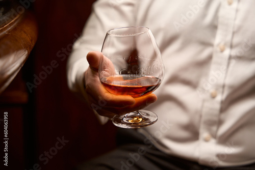 Male hand holding glass of whiskey in bar