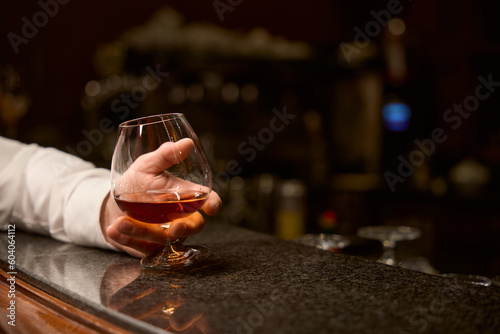 Male customer relaxing with glass of cognac at bar counter