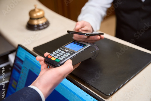 Administrator holding credit card reader, male customer making contactless payment