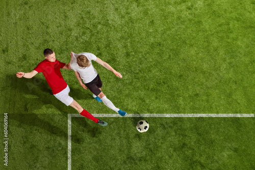 Two men, soccer players performing football play over professional stadium. All players wear unbranded clothes. Concept of professional sport