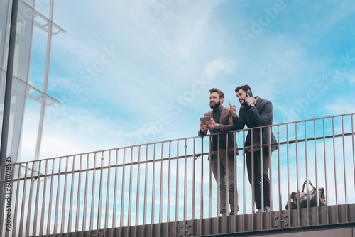 Two young contemporary businessmen outdoors city looking cityscape