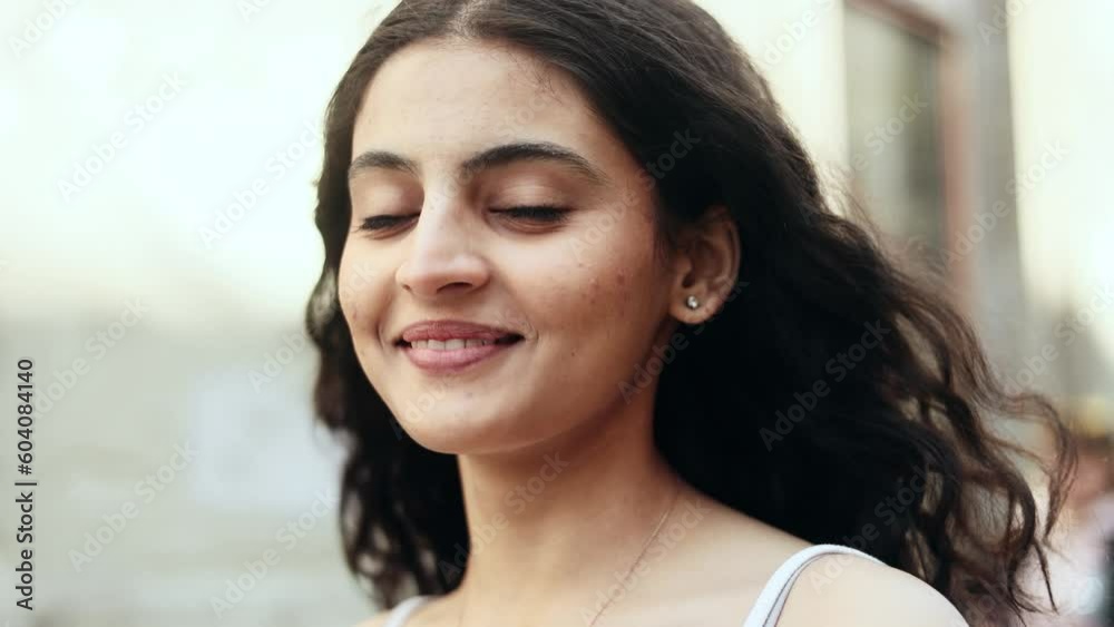 Charming young dark haired indian woman looking at the camera at the city street and enjoying beautiful day outdoors alone Pretty curly female at urban town at morning. High quality 4k footage