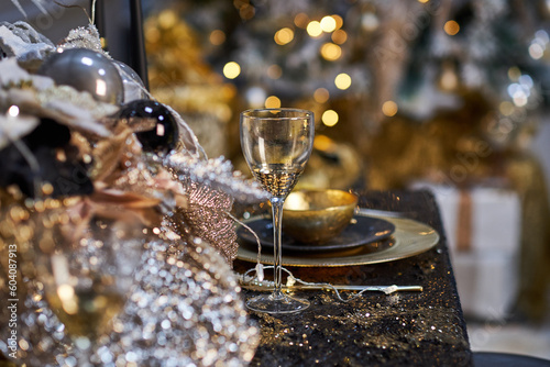 Christmas table setting with plates  silverware  gift box and decorations in black and gold colors