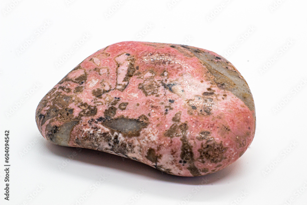 Macro focused tumbled and polished pink rhodonite crystal, manganese inosilicate mineral isolated on a white surface background Macro focused tumbled and polished pink rhodonite crystal, manganese inosilicate mineral isolated on a white surface background