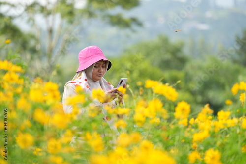 Portrait of Asian woman in a yellow flower garden and enjoying its beauty