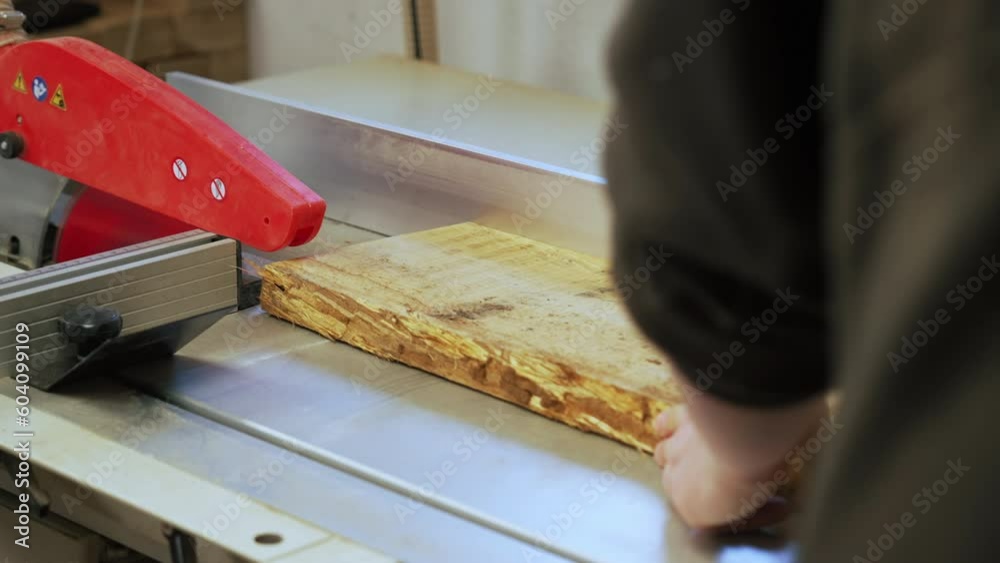 Carpenter sliding wooden plank under table saw to cut wood in woodworking studio. High quality 4k footage