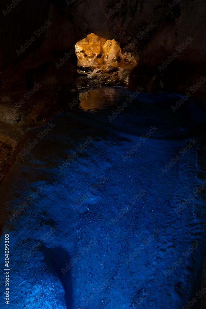 blue lake of a cavern with its entrance in the background