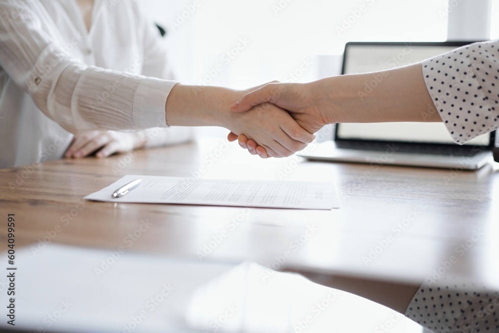 © rogerphoto - Business people shaking hands above contract papers just signed on the wooden table, close up. Lawyers at meeting. Teamwork, partnership, success concept.