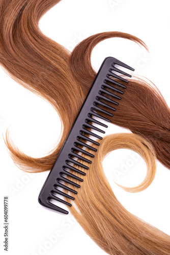 A professional black comb lies on natural curls of light and dark blond. Isolated on white background. The concept of comprehensive, salon hair care, hairdressing services