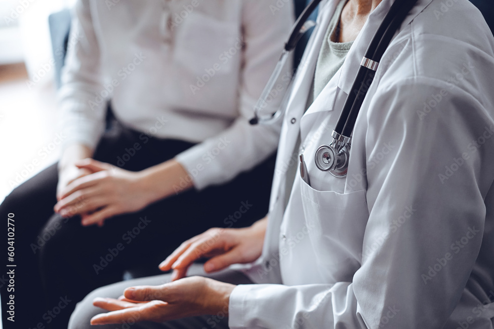 Doctor and patient discussing current health examination while sitting at the desk in clinic office, closeup. Medicine concept. Doctor and patient discussing current health examination while sitting at the desk in clinic office, closeup. Medicine concept.