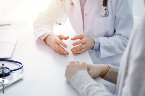 Doctor and patient discussing current health questions while sitting at the table in clinic office, only hands closeup. Medicine concept.