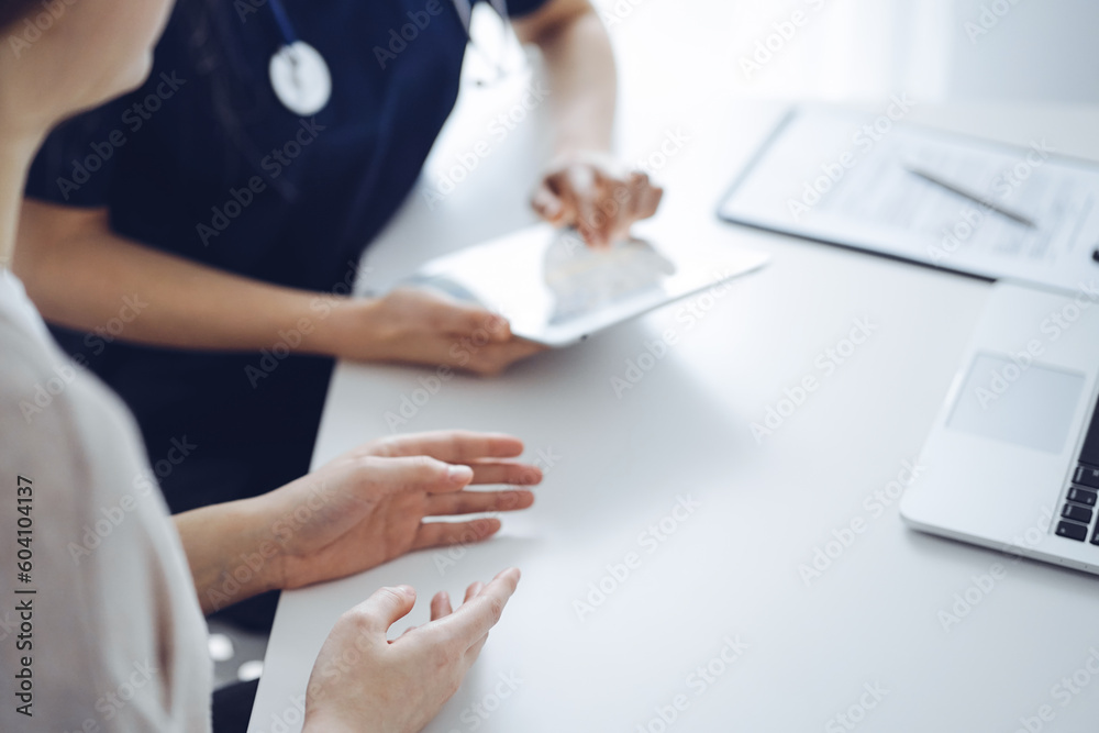 Doctor and patient talking to each other during current health examination while sitting at the desk in clinic, closeup of hand. Perfect medical service and medicine concept.