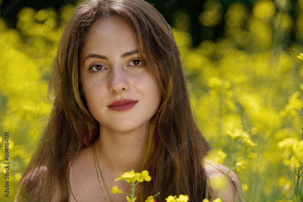 Portrait of a beautiful young woman surrounded by canola flowers. Clowe-up. Portrait of a beautiful young woman surrounded by canola flowers. Clowe-up.