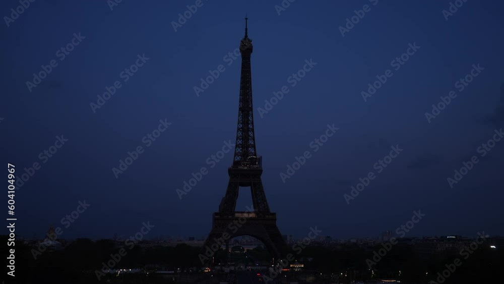Remote silhouette of the Eiffel Tower without lighting against dark sky. Iconic symbol of Paris, famous historical landmark in France. Concept of vacations in France. Shooting in slow motion.