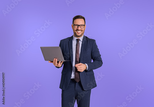 Photographie Portrait of smiling male professional manager dressed in formalwear holding laptop and looking at camera