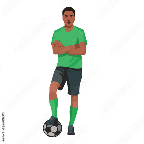 Professional african football player in a green shirt stands with his foot on the ball and his arms folded on his chest