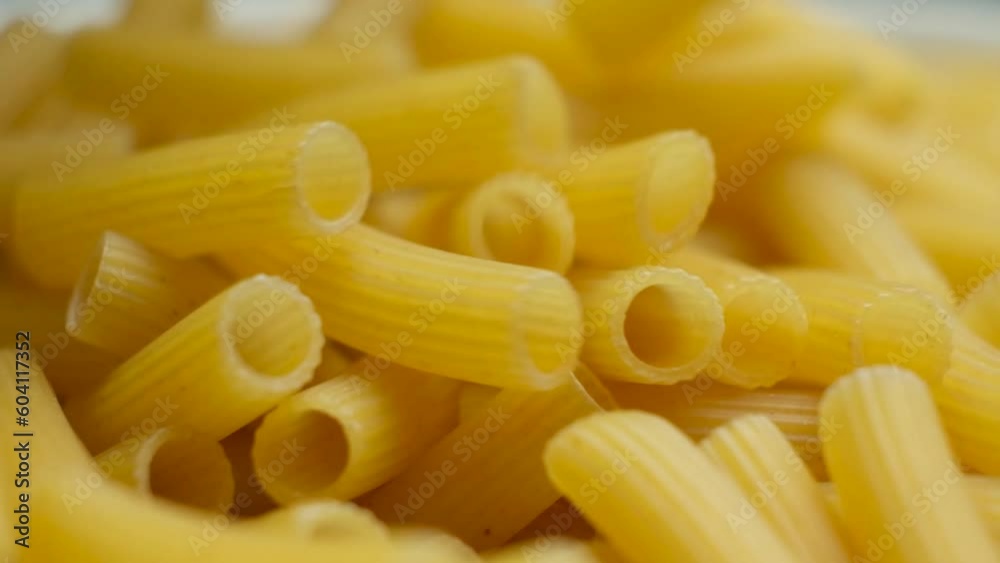 Flying wheat pasta Rigatoni in the form of tubes fall from top to bottom, close-up, slow motion shooting. Flying wheat pasta Rigatoni in the form of tubes fall from top to bottom, close-up, slow motion shooting.