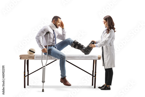 Female doctor putting on a walking brace to a male patient