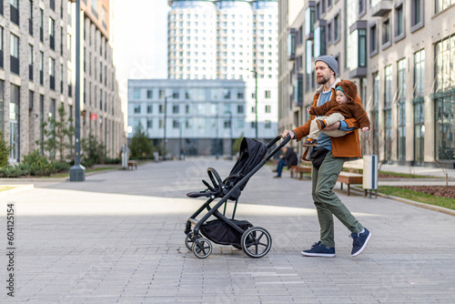A man walks down the street with a baby and stroller