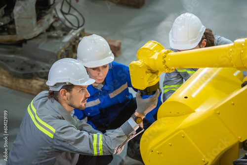 Two engineer in uniform helmet inspection check control heavy machine robot arm construction installation in industrial factory. technician worker check for repair maintenance electronic operation