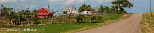 a county gravel road runs past a farm house with red barn in north eastern Colorado east of Sterling