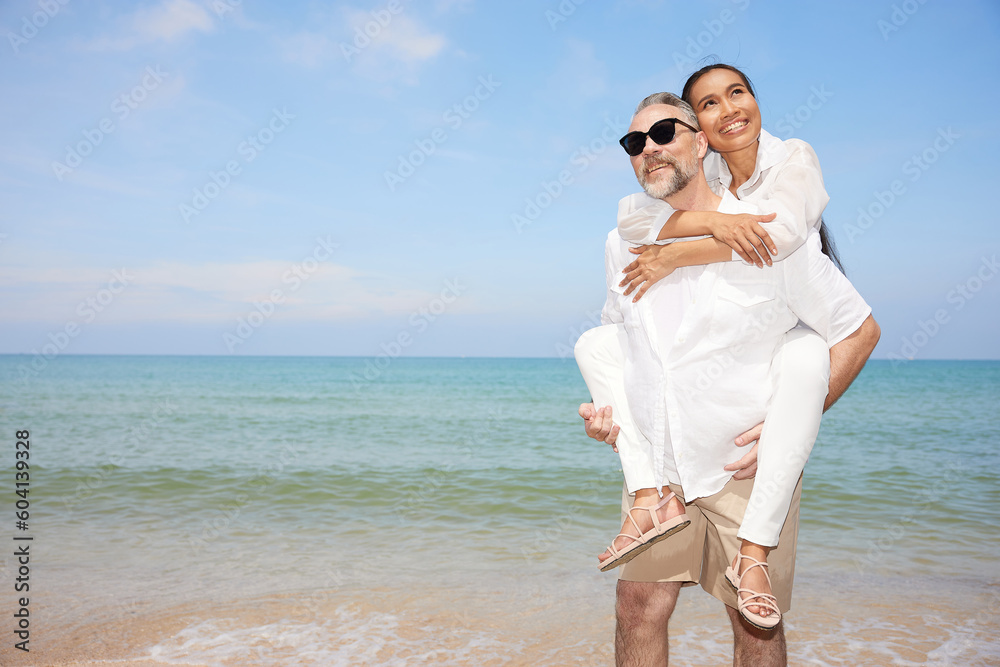elderly man carrying his girlfriend on the beach and enjoy honeymoon in summer