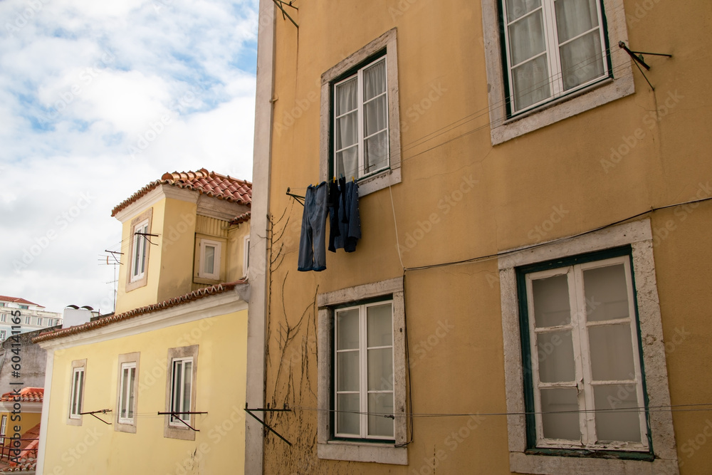 Clothes drying on a rope in the sun, facade of an old yellow historical house, clotheslines in an old town in Lisbon, Portugal