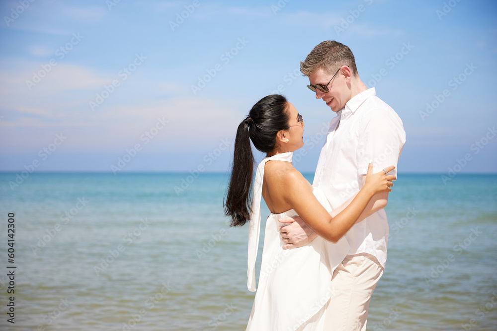 couple smiling and hugging each other on the beach