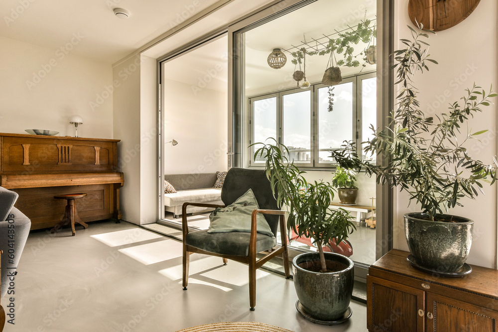 Fototapeta premium a living room with plants on the table and chairs in front of the glass door that leads to an outside patio