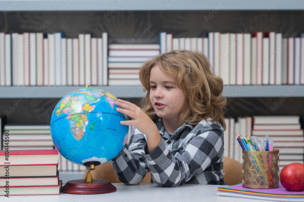 School child looking at globe in library at the elementary school. Little student school child. Portrait of nerd student with school supplies. World globe. School child looking at globe in library at the elementary school. Little student school child. Portrait of nerd student with school supplies. World globe.
