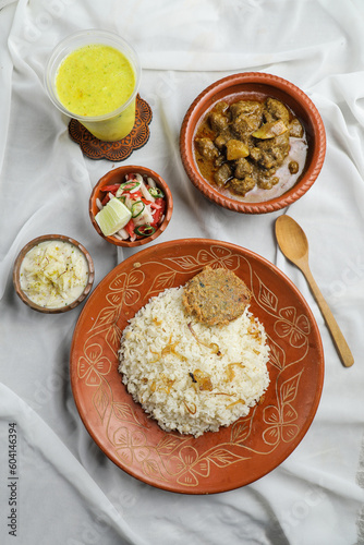 Shatkora Beef kacchi biryani khichuri with salad, borhani and Chui Pitha served in dish isolated on mat top view of indian and bangladeshi food photo